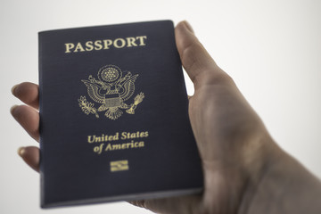 Holding Passport of USA in right hand on white background.