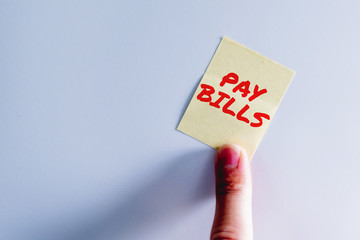 Yellow sticker inscription Pay Bills on the white fridge. Yellow note on fridge. Concept of reminder, alarm. Leaving a message,Time to pay bills.