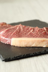 Sirloin steak beef joints on a slate cutting board on a grey wood background