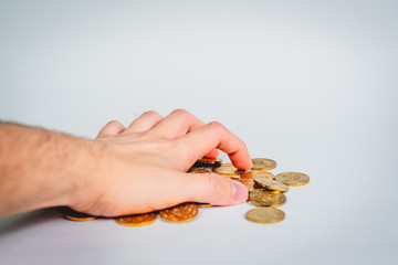 Hand greedily grabs gold coins scattered on the table. The table has gold coins, a financial and business concept. Theft, greed for money.