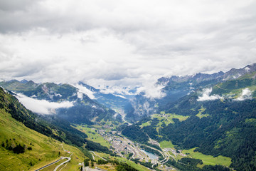 Fototapeta premium View from the top of the San Gottardo Pass to the mountain valley against the background of passing clouds