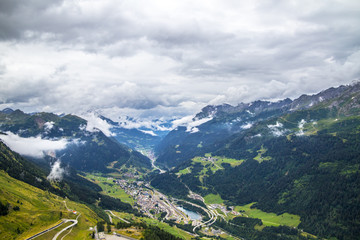 Fototapeta premium View from the top of the San Gottardo Pass to the mountain valley against the background of passing clouds