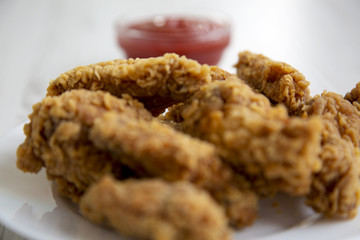 Chicken wings on a round white plate with ketchup, side view. Closeup.