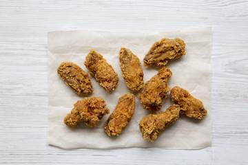 Chicken wings in paper on a white wooden table, overhead. Flat lay, top view. Close-up.