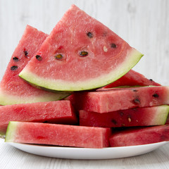 Many slices of watermelon on a white plate, closeup. Side view.