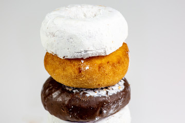 An assortment of donuts, powder donuts, chocolate donuts and plain donuts and a table waiting to be eaten