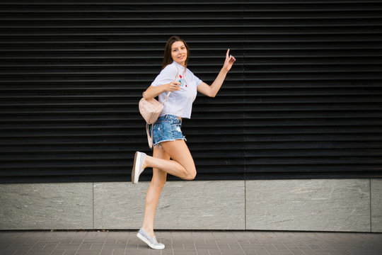 Young happy woman jump near city building wall