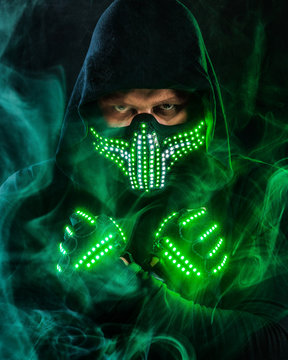 Mysterious man in black wear, neon mask and gloves. Character pastor or wizard in robe from the future. Assassin with strong face expression. Fantasy book or computer game cover concept.