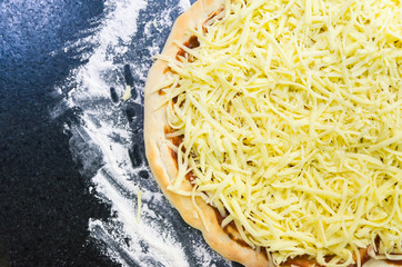 Preparing pizza, close-up of pizza dough with tomato sauce and mozzarella cheese.