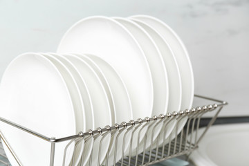 Obraz premium Different clean plates in dish drying rack on kitchen counter