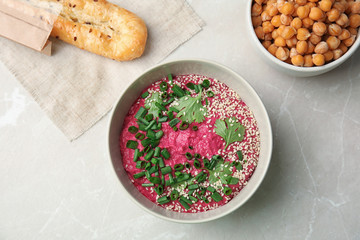 Flat lay composition with bowl of tasty beet hummus, bread and chickpea on light table