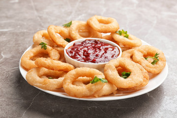 Fried onion rings served with sauce on plate