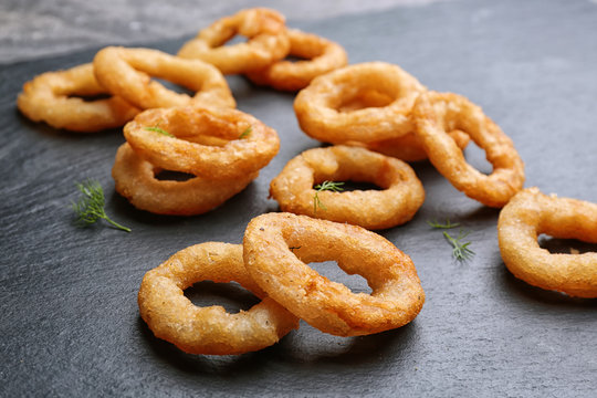 Delicious fried onion rings on table, closeup