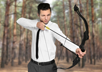 Young businessman practicing archery on white background