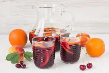 Refreshing sangria / Refreshing red wine sangria in glasses with orange fruit and peach on white...