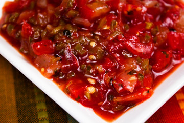 Close up of a bowl of a spicy salsa inside a white bowl. Diced tomatoes, chopped green pepper, diced onion and fresh cilantro, fresh lime juice. Perfect for chips and dip, parties.