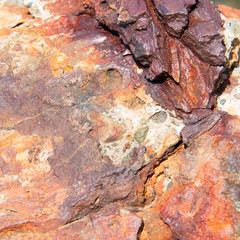 Close up weathered eroded rock stone at the beach pier. Red and brown rock texture. Wallpaper, background.