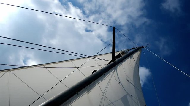sail and mast of a yacht is wobbling about in the light breeze