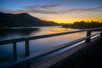 Fototapeta na wymiar Beautiful Don Pedro Lake, Through a Bridge Guardrail at Sunset