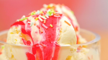 Summertime vanilla ice cream macro closeup with strawberry sauce.