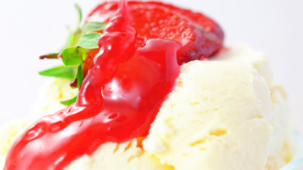 Summertime vanilla ice cream macro closeup with strawberry sauce.