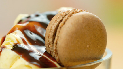Summertime vanilla ice cream macro closeup with chocolate sauce decorated with macaron cookies.