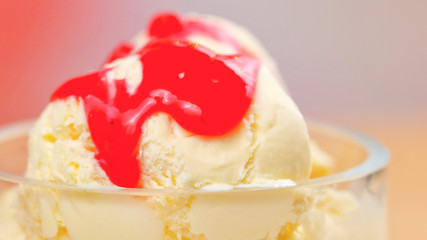 Summertime vanilla ice cream macro closeup with strawberry sauce.