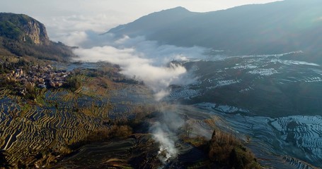 Aerial view on water-filled rice terraces and a valley covered by mist. Yuanyang Rice Terraces early in the morning during spring. 