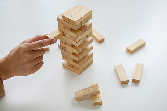 Hand of business people planning, risk and strategy in business.Businessman gambling placing wooden block on a tower.
