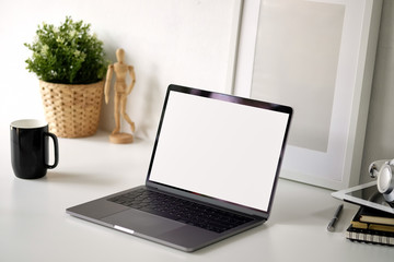 Mockup blank screen laptop and poster on white desk.