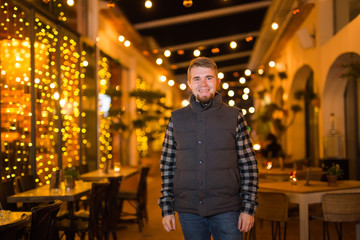 Young happy man looking at camera in the night cafe