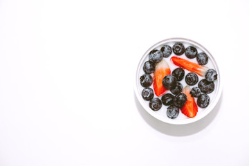 Bowl of yogurt and mixed berries blueberries with strawberries on white background