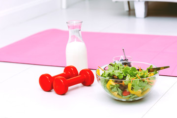 Fresh salad and dumbells on white background.Fitness and health concept