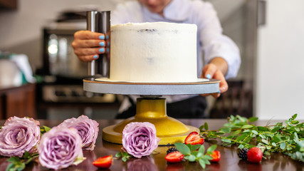 Naklejka na ściany i meble The chef's confectioner cooks a cake and decorates it with fresh flowers. background image.