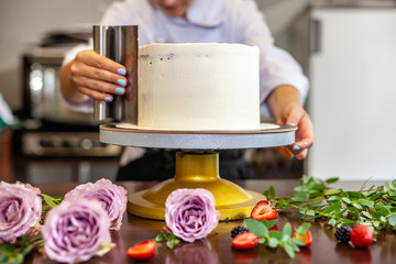 Naklejka na ściany i meble The chef's confectioner cooks a cake and decorates it with fresh flowers. background image.