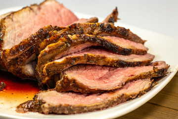Grilled tri tip steak sliced on a white plate on the kitchen table
