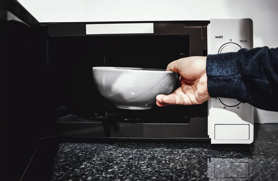 man putting bowl in microwave