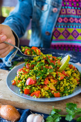 Woman hands holds Tabbouleh. Levantine vegetarian salad with parsley, tomatoes, bulgur, couscous, olive oil, lemon juice. Vegan Arabian or Israeli traditional food served as part of meze
