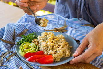 Woman hands tastes quinoa grain porridge with fork dressed with parsley, avocado, bell pepper, spices. Grown in South Africa. Traditional Peru, Bolivia non-gluten food. Raw vegan vegetarian food