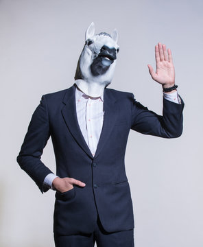 A man in a suit and a horse mask on a light background. Conceptual business background