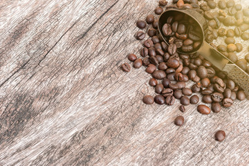 Coffee beans in the stainless steel spoon on wooden table with copy space.
