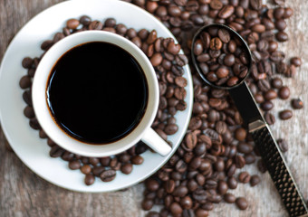 Hot coffee in white cup with coffee beans on wooden table with copy space.