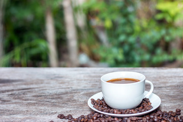 Hot coffee in white cup with coffee beans on wooden table with copy space.