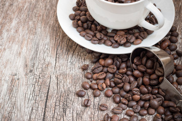 Coffee beans in white cup on wooden table with copy space.
