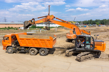 Two excavators load the earth into a dump truck