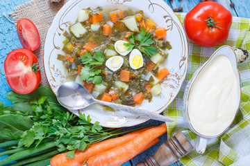Plate with sorrel soup, bread and different vegetables