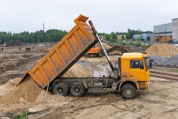 Truck unloads sand on the construction site