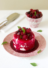 Ice cream cake with berry topping, fresh berries and mint on a light background.