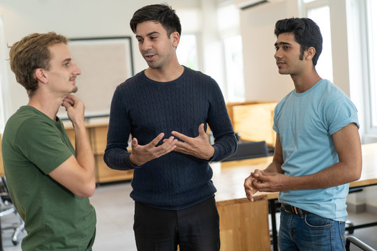 First day of internship. Mentor giving interns tour around company office. Two pensive guys listening to experienced professional in training room. Career beginning concept - Powered by Adobe