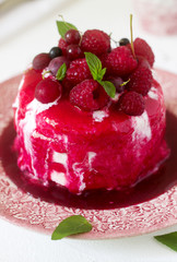 Ice cream cake with berry topping, fresh berries and mint on a light background.